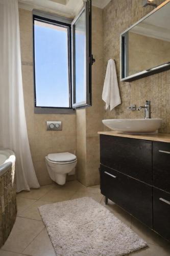a bathroom with a sink and a toilet and a window at Alkion Villa Sea View, Olive Tree Garden & Spacious Terrace in Rhodes Town