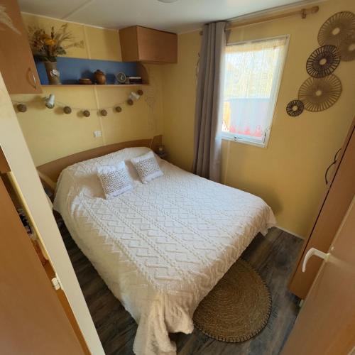 a small bedroom with a bed and a window at Chez Elvis et Agnès, logement climatisé in Saint-Loup