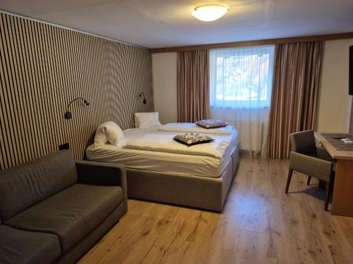 a bedroom with a bed and a couch and a window at Sporthotel Mölltal in Flattach