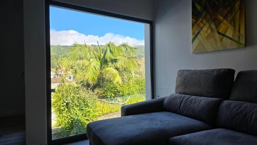 a living room with a couch and a large window at Vulcânica - Boutique Suites in Furnas São Miguel in Furnas