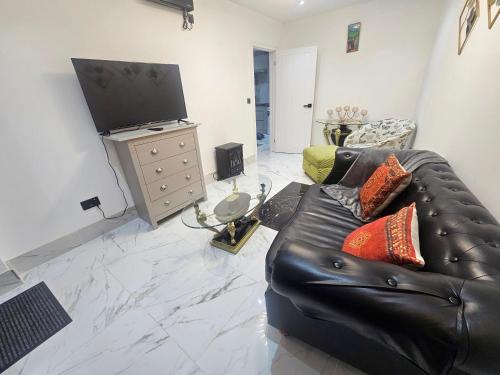 a living room with a black leather couch and a flat screen tv at Heaven in Sutton
