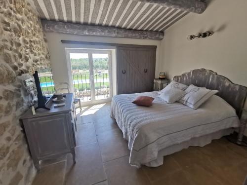 a bedroom with a bed and a desk and a window at La petite plaine in Clansayes