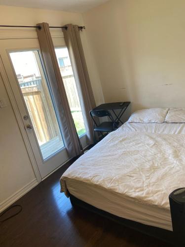 a bedroom with a bed and a window and a chair at Comfortable Room with Free Parking in Brampton