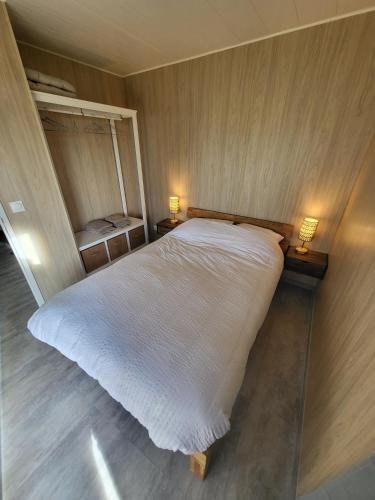 a bedroom with a large white bed with two lamps at La cabane des folies in Montmédy
