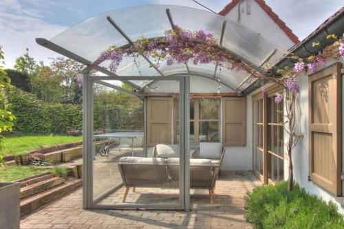 a pergola with a couch in a garden at The River Cottage in Middelkerke