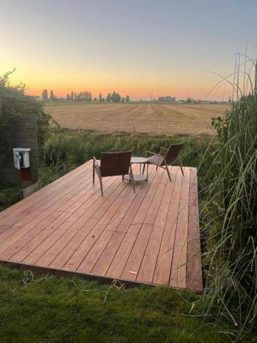 two chairs and a table on a wooden deck at The River Cottage in Middelkerke