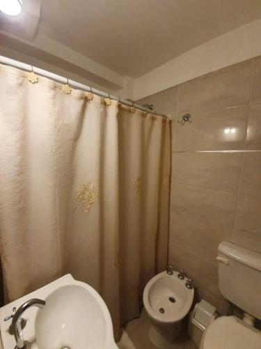 a bathroom with a toilet and a shower curtain at Mares Apart Hotel in Mar de Ajó