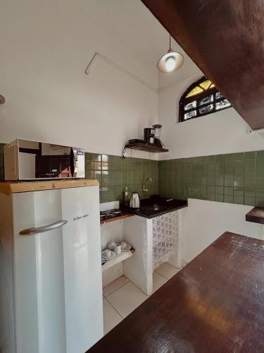 a kitchen with a white refrigerator and green tiles at Pousada Porto Búzios in Búzios