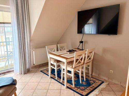 a dining room table with chairs and a television on the wall at Strandbrise App 17 in Neuhaus
