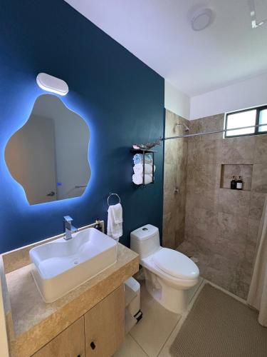 a bathroom with a sink and a toilet and blue wall at Resort living Selva Escondida II in Puerto Morelos