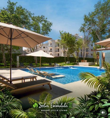 a swimming pool with chairs and umbrellas in a resort at Resort living Selva Escondida II in Puerto Morelos