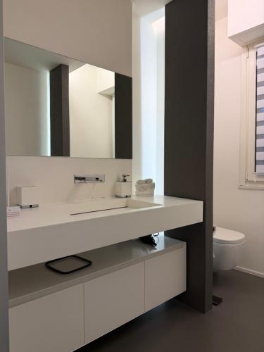 a white bathroom with a sink and a toilet at Cortirola luxury apartment in Pesaro