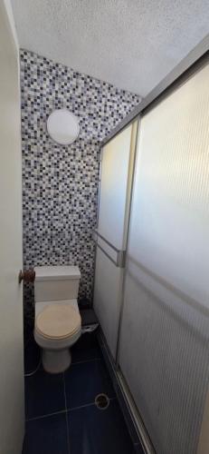un bagno con un WC e una parete piastrellata di Aguamarina a Pampatar