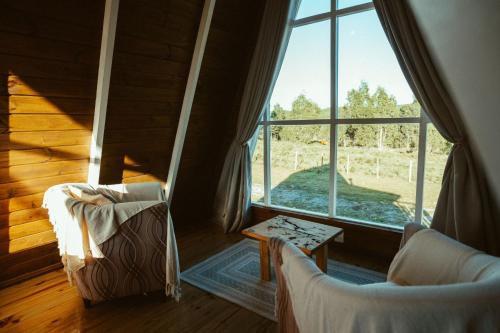 a room with two chairs and a large window at Refúgio Fortaleza - Cabana Physalis in Cambará