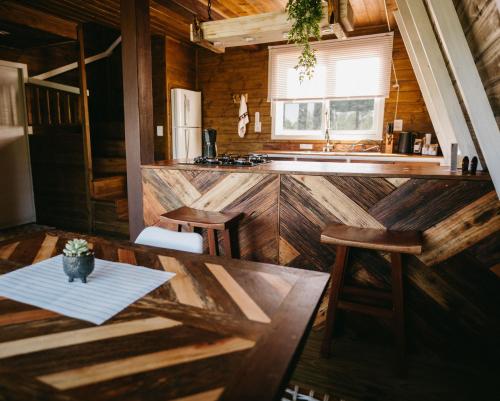 a kitchen with a table and a counter in a cabin at Refúgio Fortaleza - Cabana Physalis in Cambará