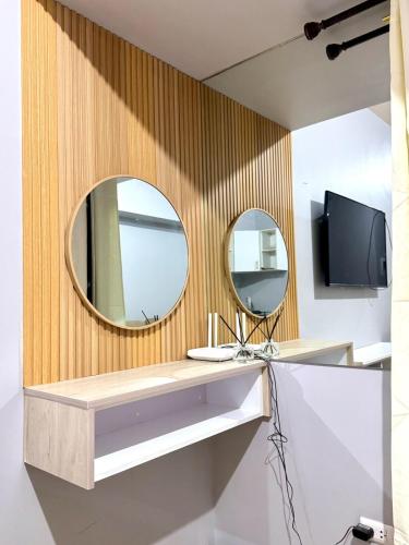 a bathroom with two mirrors and a television on a wall at Budget Friendly Centrio Tower Studio Unit PoolView in Cagayan de Oro