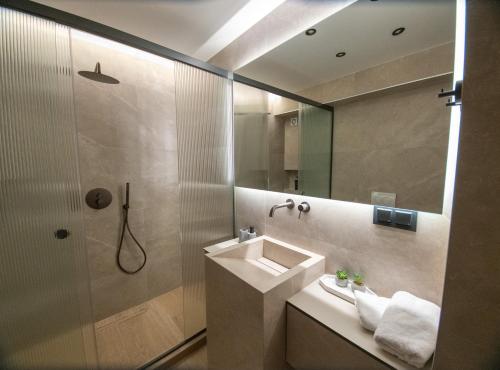 a bathroom with a sink and a shower with a mirror at Olive Home in Alexandroupoli