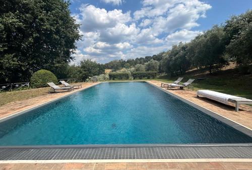 a large swimming pool with two lounge chairs next to it at Casale delle Querce in Amelia