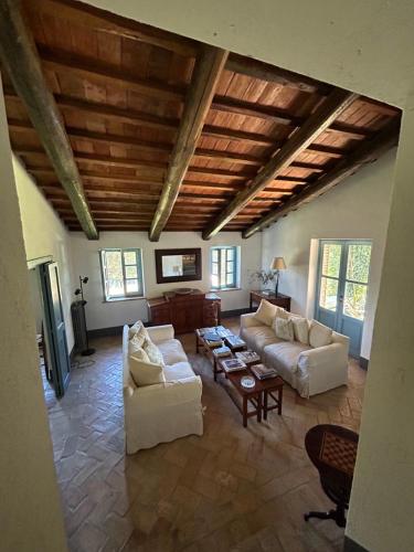 a living room with white furniture and a wooden ceiling at Casale delle Querce in Amelia