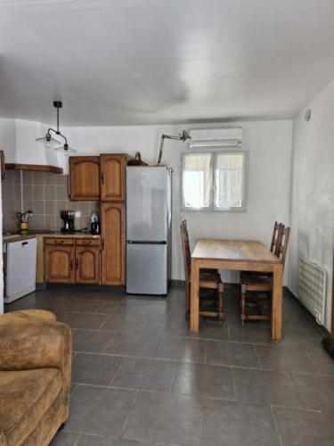 eine Küche mit einem Tisch und einem weißen Kühlschrank in der Unterkunft La petite maison in La Gaude