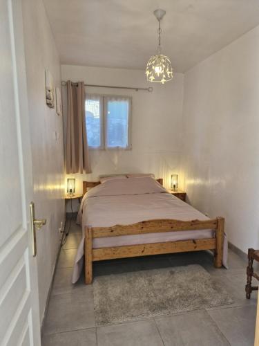 ein Schlafzimmer mit einem Bett und einem Kronleuchter in der Unterkunft La petite maison in La Gaude
