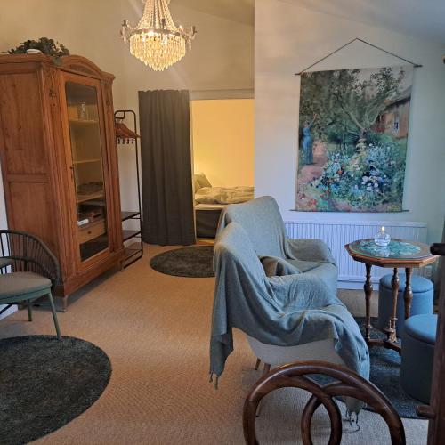 a living room with a chair and a chandelier at Cute gardenhouse close to Stockholm City in Solna