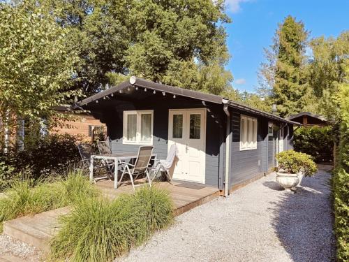 a black and white shed with a table and chairs at Gezellig ingerichte blokhut op een rustig park! in Putten