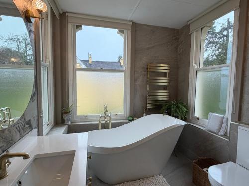 a white bath tub in a bathroom with windows at Oakhurst Guesthouse in Cobh