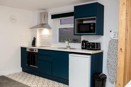 a small kitchen with blue cabinets and a sink at Stylish Studio with Parking in Doncaster in Doncaster