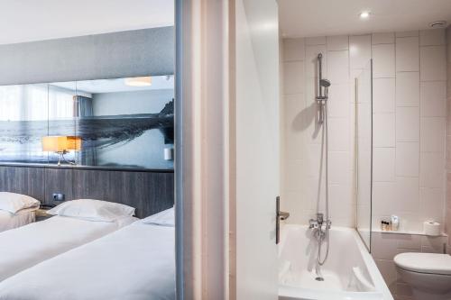 a bathroom with a bed and a bath tub next to a toilet at Hotel De La Digue in Le Mont Saint Michel