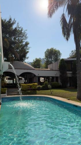 a swimming pool with a fountain in front of a building at Hotel Mythos in Tepoztlán