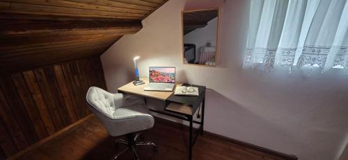 a desk with a laptop and a chair in a room at Refúgio no Vale das Furnas - Casa do Sossego in Furnas