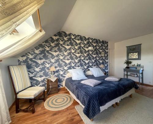 a bedroom with a large bed and a chair at Grand Mainguet in Saint-Lambert-la-Potherie