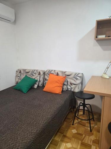 a bed with two colorful pillows on it in a room at Prelep mali stan sa terasom in Petrovaradin