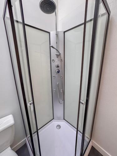 a shower with a glass enclosure in a bathroom at Studio Neuf Centre - Chambre Séparée - Parking in Bressuire