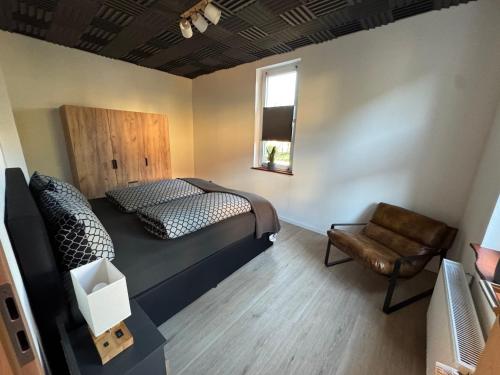 a bedroom with a bed and a chair and a window at Canossa Lodge in Bad Harzburg
