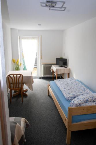 a bedroom with a bed and a table and a television at Zimmervermietung Peter in Zirndorf