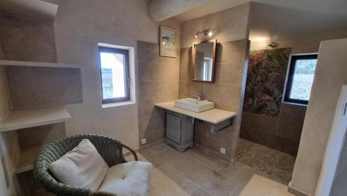 a bathroom with a wicker chair and a sink at La Fabrique in Gargas