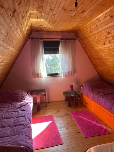a attic room with two beds and a window at Kuća za odmor VITICA s vanjskim kaminom in Kupres