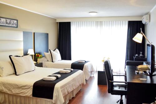a hotel room with two beds and a desk at Pocitos Plaza Hotel in Montevideo