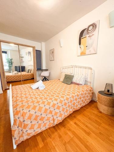 a bedroom with a bed with a orange comforter at À deux pas du métro in Paris