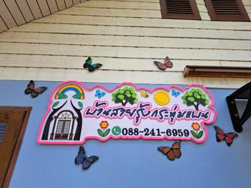 a sign on the side of a building with butterflies at บ้านสายรุ้ง กระทุ่มแบน in Samut Sakhon