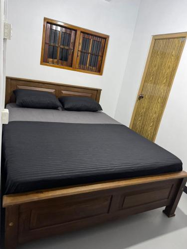 a bed with a wooden frame and a window at Dilco Villa Ahangama in Ahangama