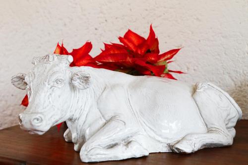 a white statue of a cow sitting on a table with a red flower at Hacienda Panoaya in Amecameca de Juárez