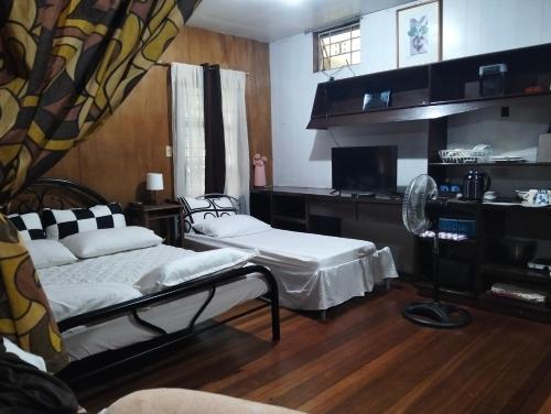 a room with two beds and a desk with a fan at Jenny's transient house in Baguio