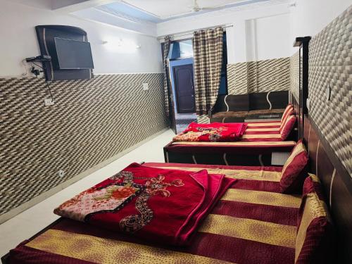 a room with two beds and a television in it at Hotel Amrit in Bharwain