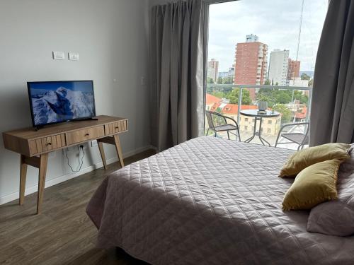 a bedroom with a bed and a desk with a television at Estudio 63 in Neuquén