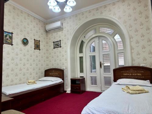 a bedroom with two beds and a large window at Imran Guest House in Samarkand