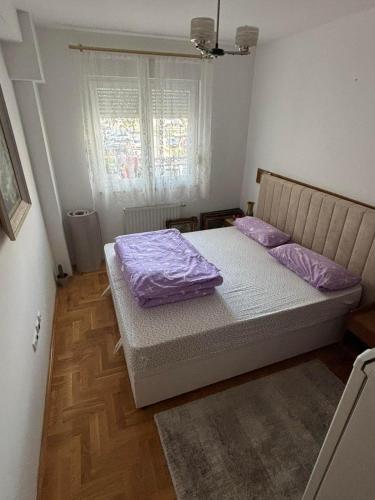 a bedroom with a bed with purple sheets and a window at Lana in Trebinje