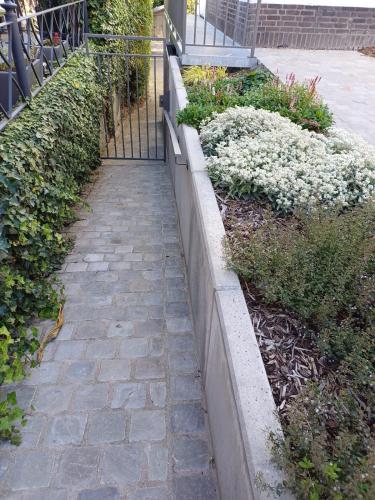 a stone walkway next to a fence with flowers at Gastenverblijf Onder een Oude Eik in Tongeren
